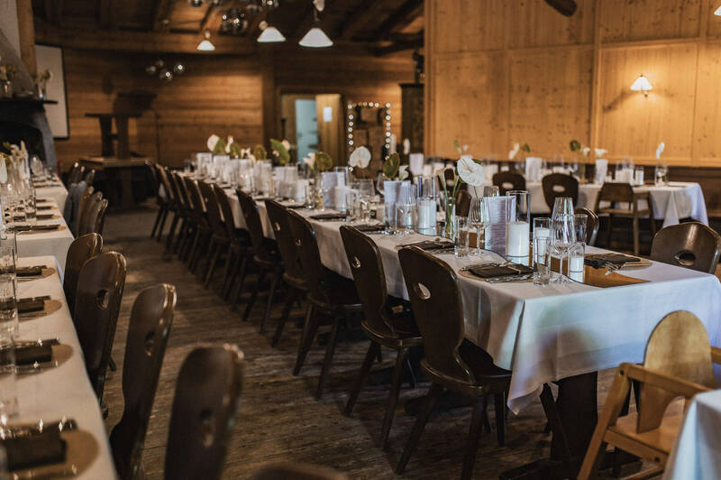 In der Hütte sind mehrere Tische festlich für eine Hochzeit dekoriert.