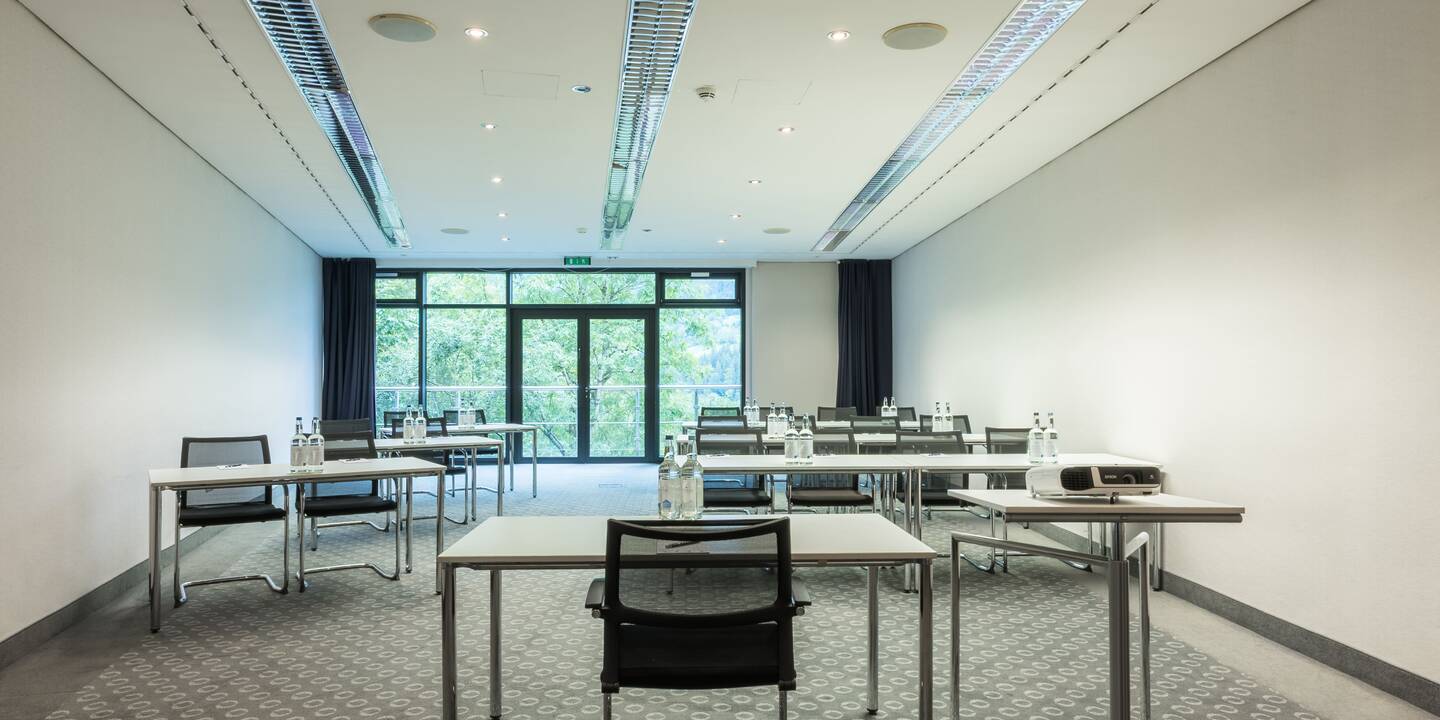 Tagungssalon im AlpenCongressCenter des AllgäuSternHotels mit angeordneten Tischen und Fensterfront im Hintergrund.