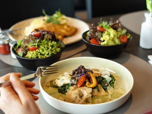 Two plates with dishes and two salads on a table