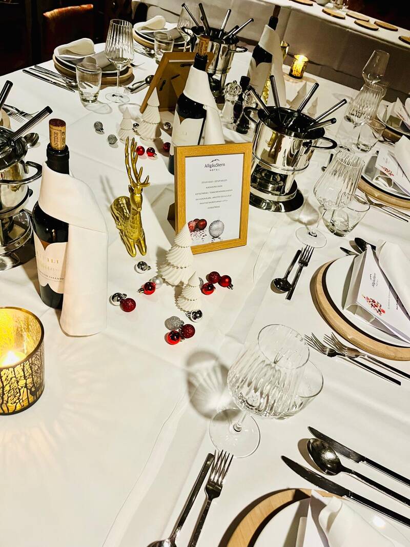 Festlich gedeckte Tafel im AllgäuSternHotel mit Fondue und Weihnachtsdeko.