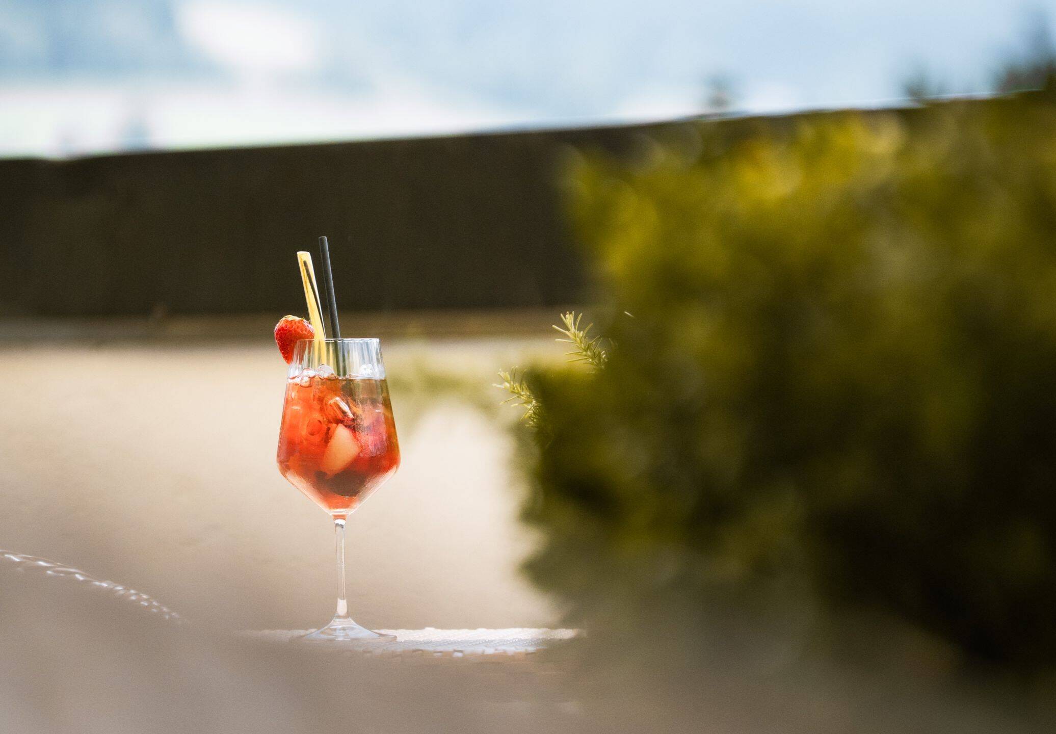 A glass of homemade strawberry punch is standing on a terrace table at the AllgäuSternHotel.