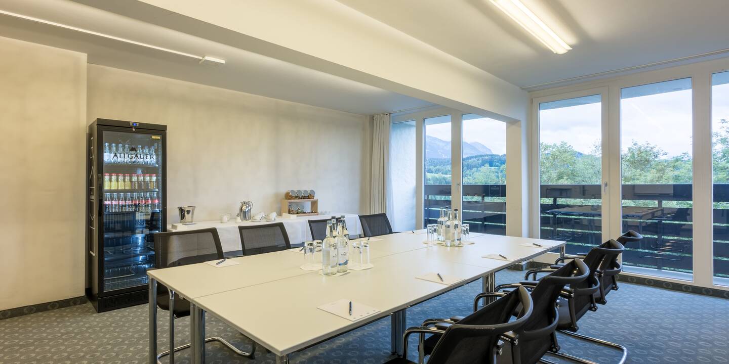Workshopraum im AllgäuSternHotel mit angerichteter Candybar, gefülltem Kühlschrank und Tischblöcken in der Mitte des Raums, im Hintergrund ein Balkon mit Blick in die Natur.