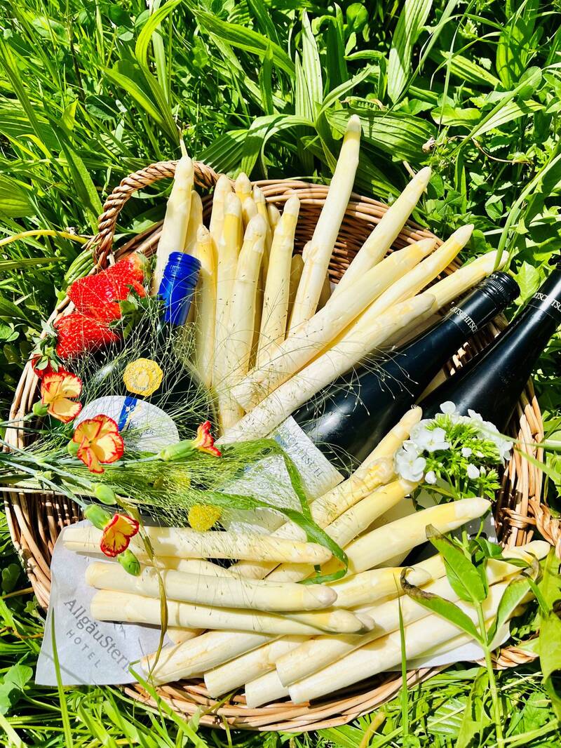 Ein schön dekorierter Korb mit frischem Spargel und Weißwein im Rahmen des Tagungsangebots für den Frühling.