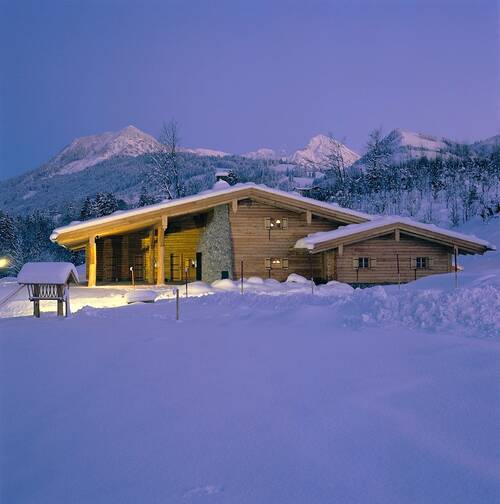 Die Sonnenkopfhütte des AllgäuSternHotels mit schneebedeckten Wiesen und Bergen.
