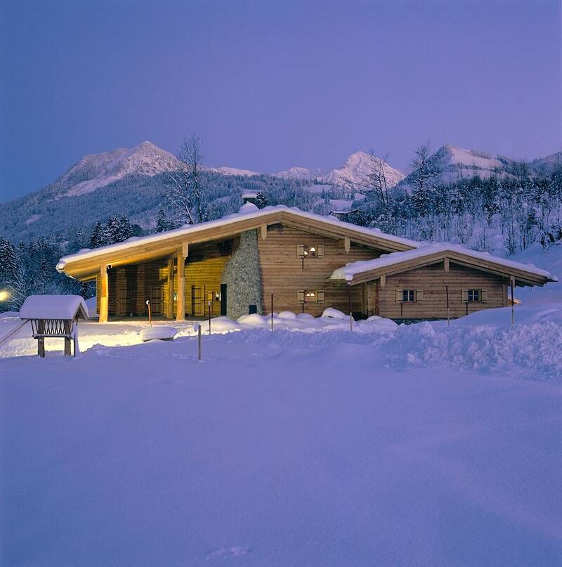 Die Sonnenkopfhütte des AllgäuSternHotels mit schneebedeckten Wiesen und Bergen.