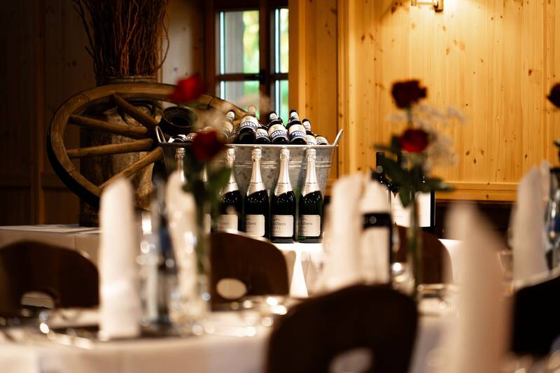 Die Sonnenkopfhütte ist festlich für eine Hochzeit dekoriert mit gedeckten Tischen, roten Rosen und Sektflaschen.